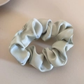Detalle de scrunchie de seda verde salvia con brillo satinado y textura de tela plisada - Verde