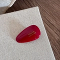 Macro view of dark red teardrop acetate hair clip with gold France Handmade lettering - Red