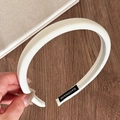 Nahaufnahme eines handgefertigten weißen Satin-Schwamm-Stirnbands mit seidiger Textur - Milchweiß