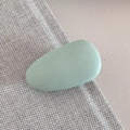Close-up of a mint green matte pebble-shaped hair clip with smooth elegant texture - Green