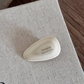 Macro view of teardrop acetate hair clip with gold France Handmade engraved text on linen - Milk White