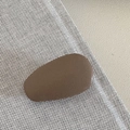 Close-up of matte brown drop-shaped leather hair clip on beige woven fabric - Brown