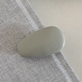 Detail of matte cream droplet hair clip showing smooth texture on woven and leather background - Khaki