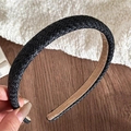 Close-up of black braided headband featuring faux leather weave and soft brown lining - Black