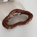 Detailed top view of brown satin fabric wrapped shark hair claw on leather background - Coffee Irregular Shape