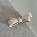 Close-up of a matte pink bow hair clip with elegant texture on a neutral fabric background - Candy Knot Duckbill / Beige