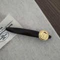 Macro view of matte black hair clip featuring an antique gold coin emblem detail - Gold Round Ornament / Dark Coffee