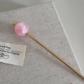 Detail van een gouden metalen haarstokje met een doorschijnende roze glitter kraal - Roze