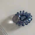 Dettaglio macro di un elastico a spirale blu cangiante con una perla decorativa trasparente - Blu