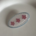 Détail de la barrette ovale bleue à bords ondulés avec motifs de fleurs roses - Fleur Rose