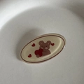 Detail shot of a cute cartoon bear holding a red heart on a cream oval hair clip - Bear with Heart