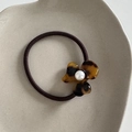 Detailed view of acetate flower hair tie with tortoiseshell texture and pearl center - Dark Tortoiseshell