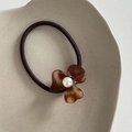 Detail view of a vintage amber acetate flower hair tie with a central pearl embellishment - Tortoise