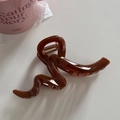Detailed view of the dark amber resin hair claw clip with its glossy wave design - Line-Coffee