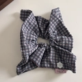 Dettaglio dell'elastico a quadretti con bottone a fiore bianco e etichetta rosa - Quadri Blu Marino e Rosso