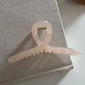 Primer plano de pinza de pelo rosa translúcida con resorte dorado sobre fondo de lino - Rosa Claro