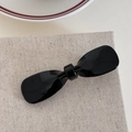 Detail view of a glossy black acetate bow hair clip on a minimalist linen fabric background - Black Bow