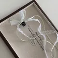 Détail d'une mini pince à cheveux avec dentelle blanche et ruban vert sur plateau - Vert Clair