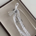Détail d'une pince à cheveux avec nœud en dentelle blanche et rubans sur un écrin à bijoux - Blanc Crème