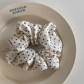 Close-up of cream satin scrunchie with black polka dots on a ceramic plate - White Polka Dot