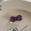 Close-up of a purple jelly resin bow hair tie placed on a decorative cream floral plate - Duckbill Hair Clips / Purple
