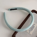 Detalle de diadema de tela azul claro con etiqueta hecha a mano sobre material tejido - Verde