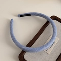 Detail of light blue twill fabric headband with a black handmade label on white desk - Blue