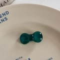 Detail of a translucent dark green resin bow hair tie on a decorative ceramic plate - Duckbill Hair Clips / Green