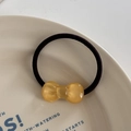 Detailed close-up of a high-elastic black hair tie with a translucent amber resin bow - Hair Tie / Yellow