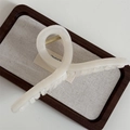 Detail view of the durable golden metal spring on a cream-colored hair claw clip - White