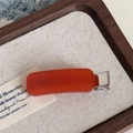 Close-up of orange acetate hair clip with a silver metal base on a beige linen display tray - Rectangle Candy Clip / Orange