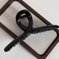 Detail of a 14.5cm glossy black hair claw clip on a wooden tray with elegant text - Black
