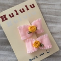 Dettaglio di fermagli per capelli in raso rosa con rose in tessuto giallo su cartoncino - Fiocco Rosa con Piccola Rosa
