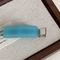 Macro shot of matte sky blue rectangle hair clip with silver metal duckbill base - Blue