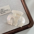 Macro detail of a pearl white acetate hair claw clip with French design on linen - Mermaid White