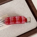 Macro view of a red and pink checkered acetate hair clip with a silver metal duckbill base - Red Check