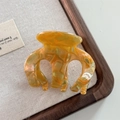 Detail view of amber acetate hair claw clip with elegant texture on linen surface - Orange Green