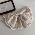 Detailopname van beige kanten strik haarspeld met opengewerkte borduurmotieven - Veerclips / Kant Beige