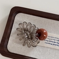 Détail d'un élastique spirale gris avec une perle décorative marron sur bois élégant - Marron