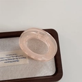 Detail view of pink translucent camellia claw clip with polished finish on wooden tray - Translucent Pink Claw - O-Shape