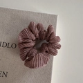 Dettaglio ravvicinato della trama plissettata di un elastico in seta color malva - Rosa Arancio
