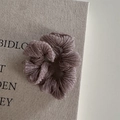 Close-up of pleated metallic hair scrunchie with shimmering texture on a book cover - Bean Paste