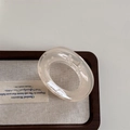 Detail of a translucent beige oval hair claw clip with a glossy finish on a wooden tray - Translucent Beige Claw - O-Shape