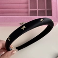 Detail eines gepolsterten schwarzen Satin-Haarreifs mit goldenen Schleifen und Rutschschutz - Schwarzes Stirnband mit Goldener Schleife
