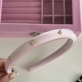 Detail eines rosa Satin-Haarreifs mit goldenen Schleifen auf einer Schmuckbox - Rosa Stirnband mit Goldener Schleife