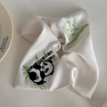 Makroaufnahme von gestickten Panda- und Bambusmotiven auf einem weißen Seidenhaargummi - Beige (Panda Eckiger Haargummi)