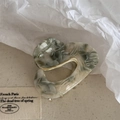Detail of irregular heart-shaped acetate hair claw with grey and white marble texture - Beige Green
