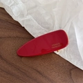 Detailed close-up of handmade red acetate triangle hair clip with golden metal accents - Red