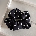 Detailopname van zwart-witte satijnen scrunchie met stippen op een display plateau - Haarelastiek / Print Stippen Zwart