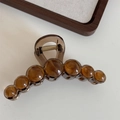 Detailed view of amber resin hair claw clip with round bead accents and gold metal spring - Brown